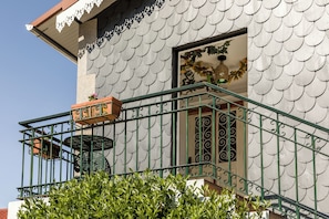 Ein Gebäude mit Kachelfassade, einem Balkon mit schmiedeeisernem Geländer und einem Fenster mit dekorativen Fensterläden.