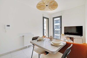 Un comedor moderno con una mesa dispuesta para dos personas, un televisor y una ventana con vistas.