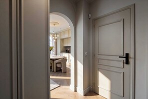 A hallway leading to a dining area with a round table and chairs, a kitchen in the background, and a white door with a black handle. - Modern, A/C Apartment - 2bdr/4p - Cannes/beach (Cannes)