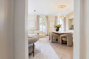 A modern living room with a sofa, a dining table with chairs, a chandelier, and a vase with flowers. - Modern, A/C Apartment - 2bdr/4p - Cannes/beach (Cannes)