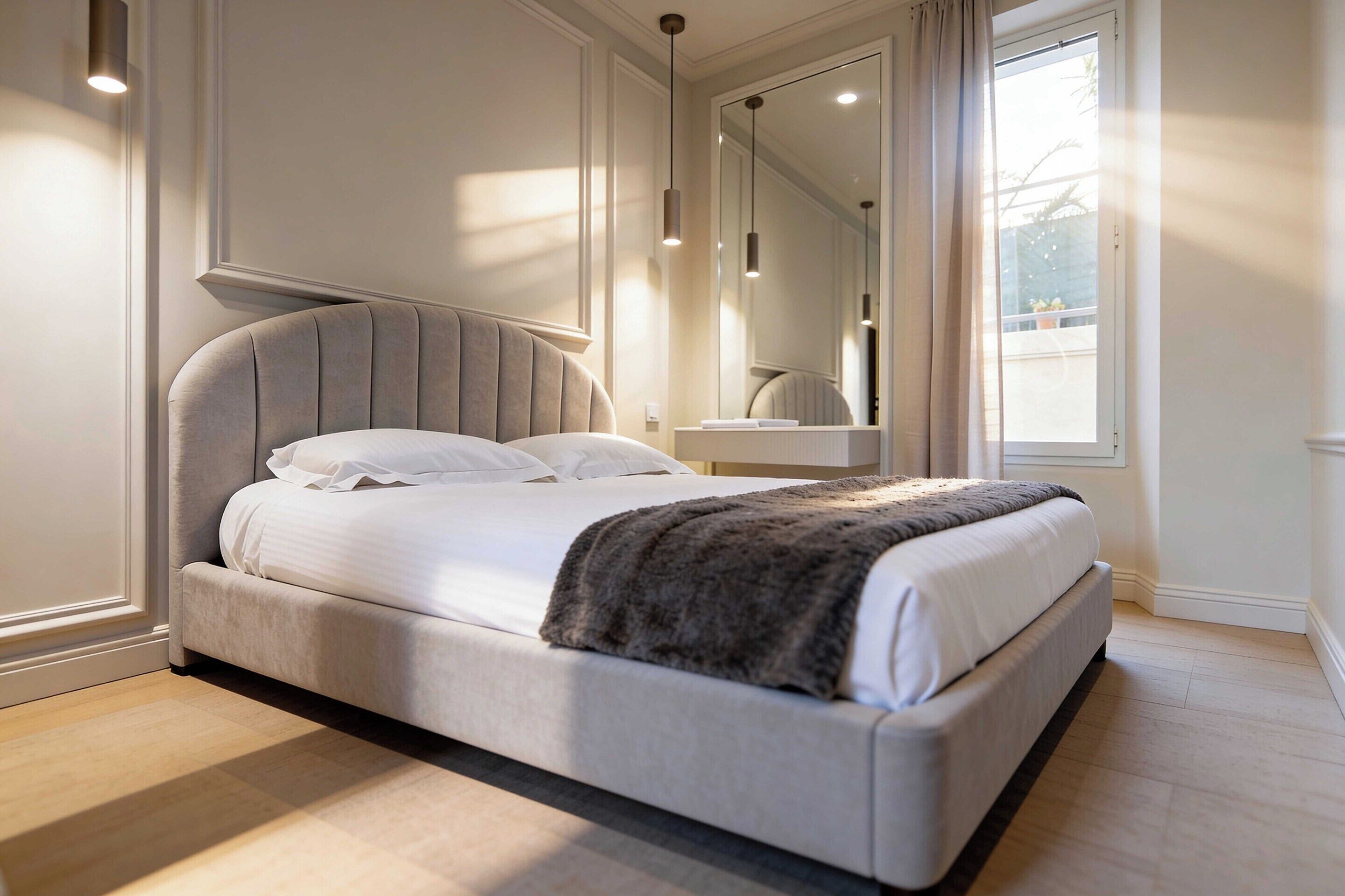 Een moderne slaapkamer met een groot bed, een nachtkastje, een spiegel en een raam met gordijnen.