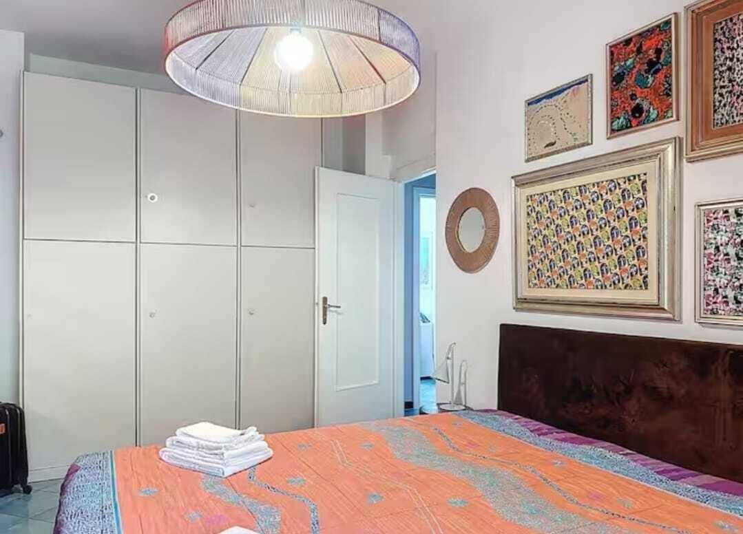 Una camera da letto con un letto, un armadio, una lampada a soffitto e opere d'arte alle pareti.