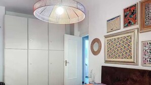 A bedroom with a bed, a wardrobe, a ceiling light, and wall art.