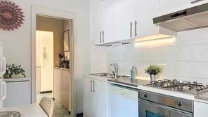 A modern kitchen with white cabinets, stainless steel appliances, and a visible dishwasher.