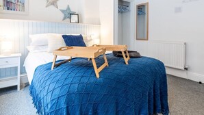Ein Schlafzimmer mit Bett, Nachttischen, Schminktisch, Kommode, Spiegel und einer Stern-Dekoration an der Wand.