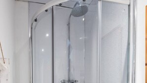 Eine Duschkabine mit Handbrause, ein weißes Waschbecken und ein Handtuchhalter.