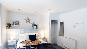 Ein Schlafzimmer mit einem Bett, Nachttischen, einem Heizkörper, einer Stern-Dekoration und einem gerahmten Bild an der Wand.