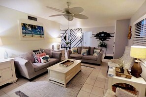 Ein Wohnzimmer mit zwei Sofas, einem Couchtisch, einem Deckenventilator und einem Bild an der Wand.
