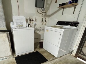 A laundry room with two white washing machines, a black mat, and a shelf with items on it. - Coastal 2-bed Bungalow with Comfy King's, a Steamy Spa & AC in sunny Cape Coral (Cape Coral)