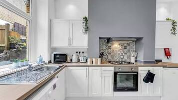 A modern kitchen with white cabinetry, a built-in oven, and a dishwasher.