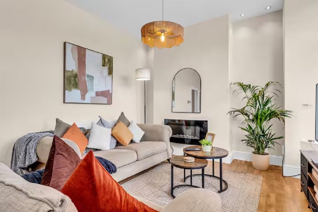 A modern living room with a sofa, coffee table, and a large potted plant.
