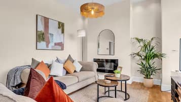 A modern living room with a sofa, coffee table, and a large potted plant.
