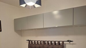 Een slaapkamer met een bed, twee nachtkastjes met lampen, een plafondarmatuur en inbouwmeubels boven het bed.
