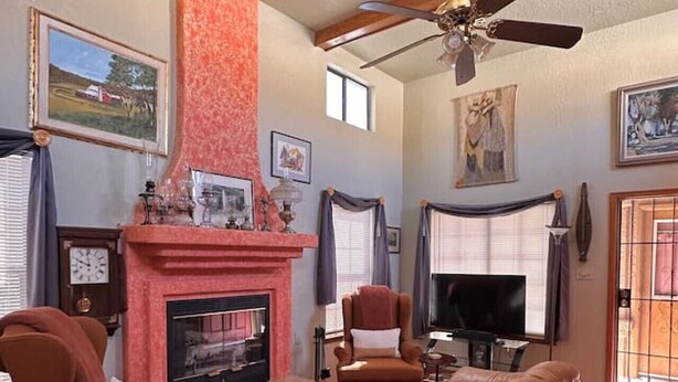 Una sala de estar con chimenea, ventilador de techo y televisor.