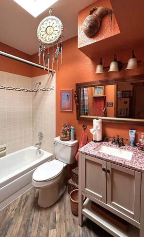 Ein Badezimmer mit Badewanne, Toilette, Waschtisch und Deckenleuchte.