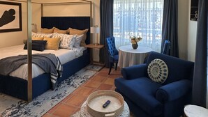 Una habitación de hotel con cama, sofá, una mesita y ventana con cortinas.