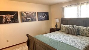Une chambre à coucher comprenant un lit, une table de chevet, une lampe et trois tableaux représentant des animaux, accrochés au mur.
