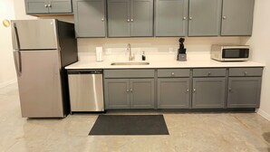 A modern kitchen with grey cabinets, stainless steel appliances, and a white countertop. - Novel King Suite- Central West End near SLU 101 (St. Louis)