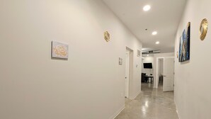 A hallway with white walls, a polished floor, and artwork. - Novel King Suite- Central West End near SLU 101 (St. Louis)