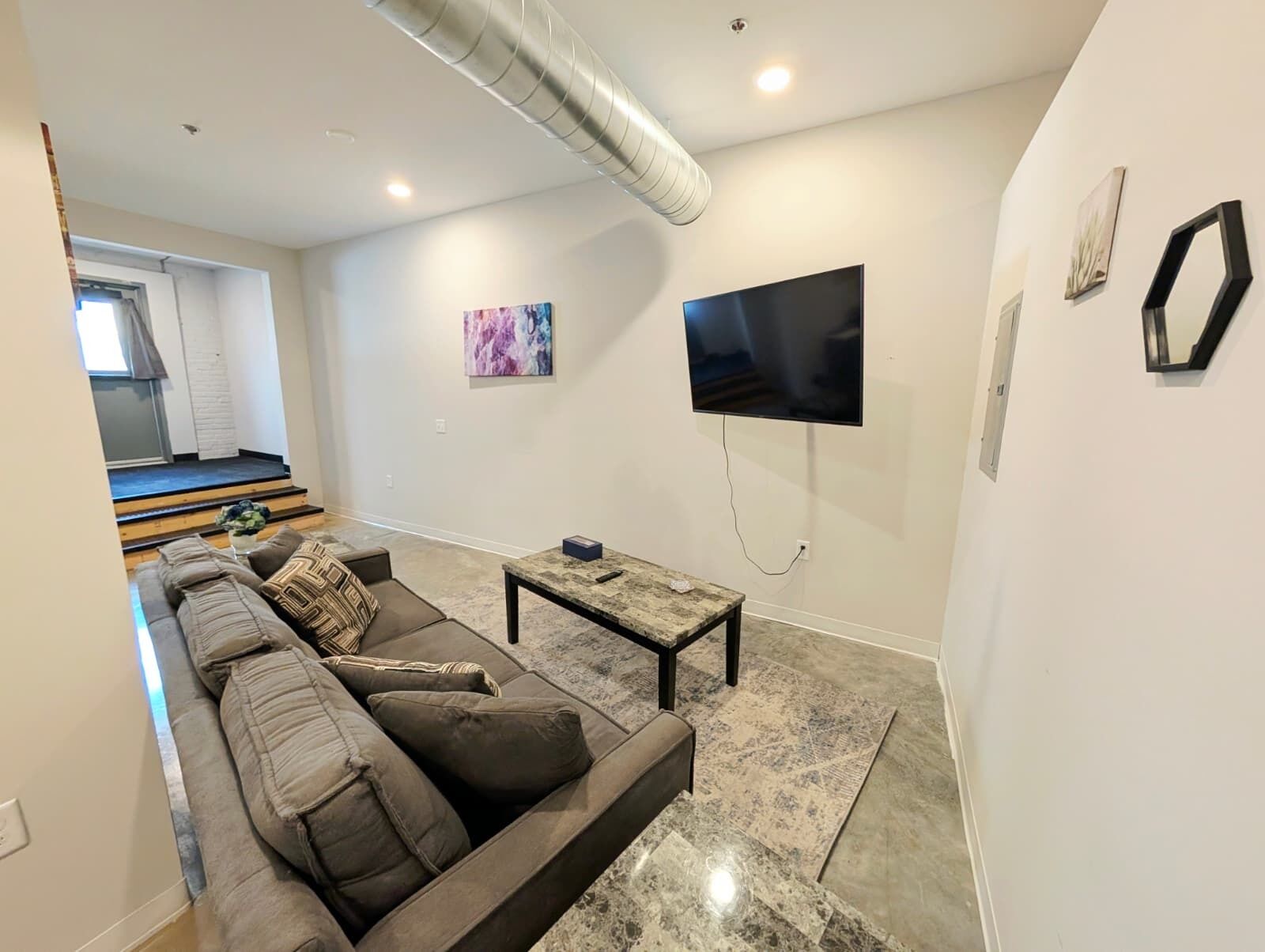 Una sala moderna con sofá, mesa de centro y televisor montado.