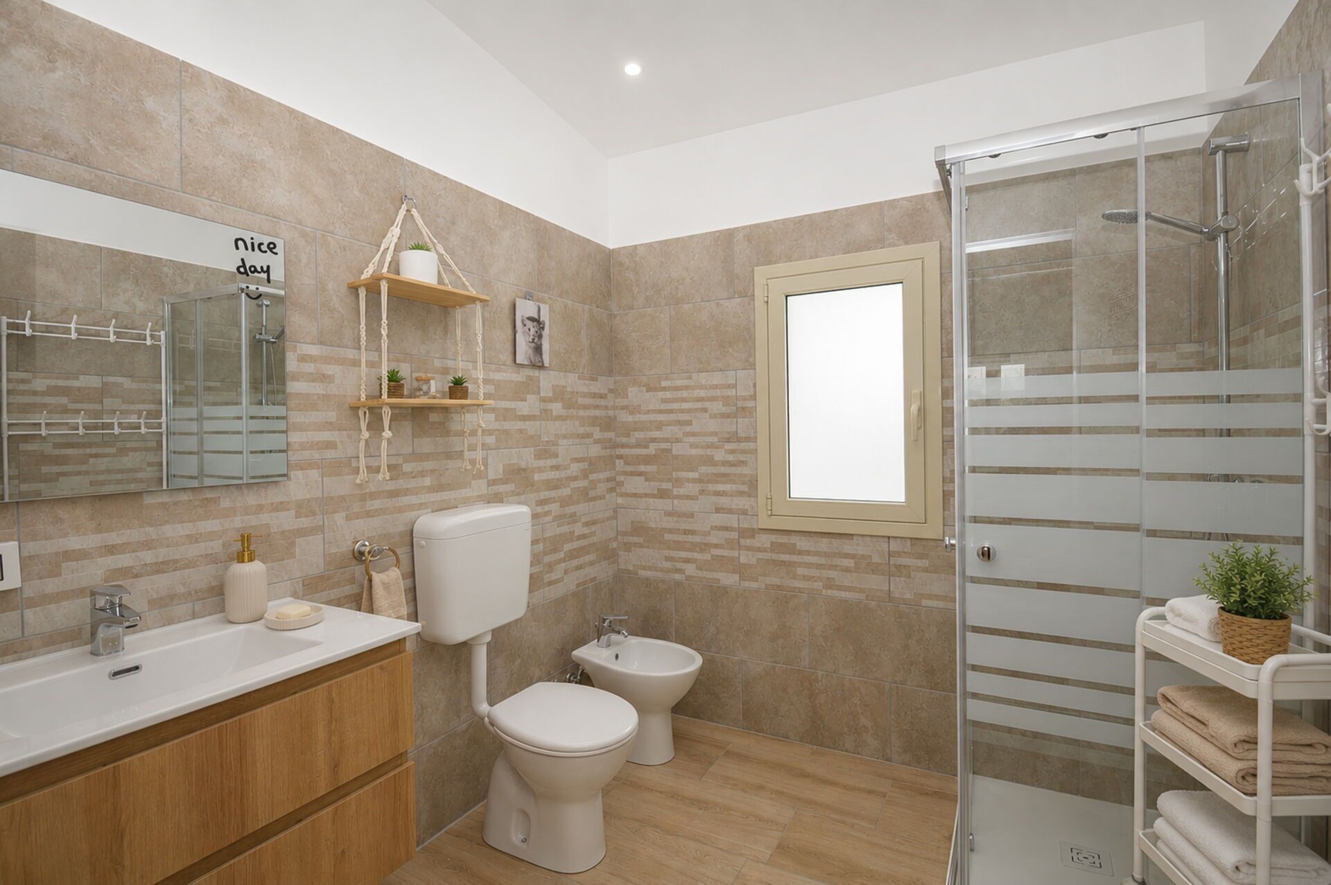Une salle de bain moderne équipée d’une douche, de toilettes, d’un bidet et d’un meuble-lavabo avec un évier et un porte-serviettes.