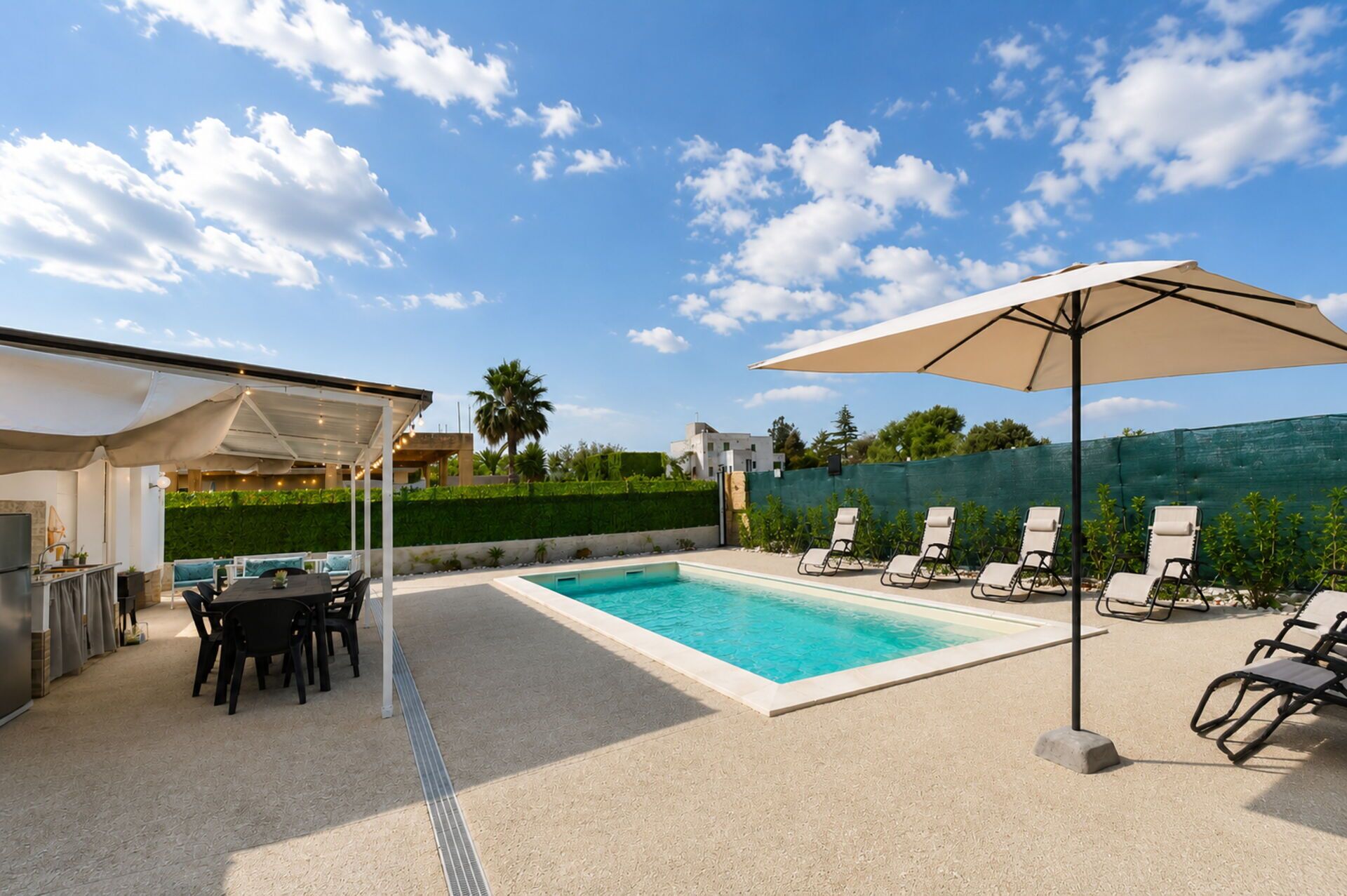 A swimming pool with lounge chairs and a covered patio area.