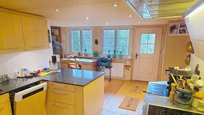 Una cucina con mobili in legno, un piano di lavoro nero, un forno e un angolo pranzo con tavolo e sedie.