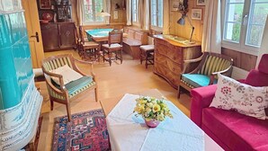 Una stanza accogliente con un tavolo da pranzo in legno, sedie, un divano e un'ampia finestra.
