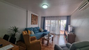 Un salon comprenant un canapé, des fauteuils, une table basse et un meuble pour la télévision.