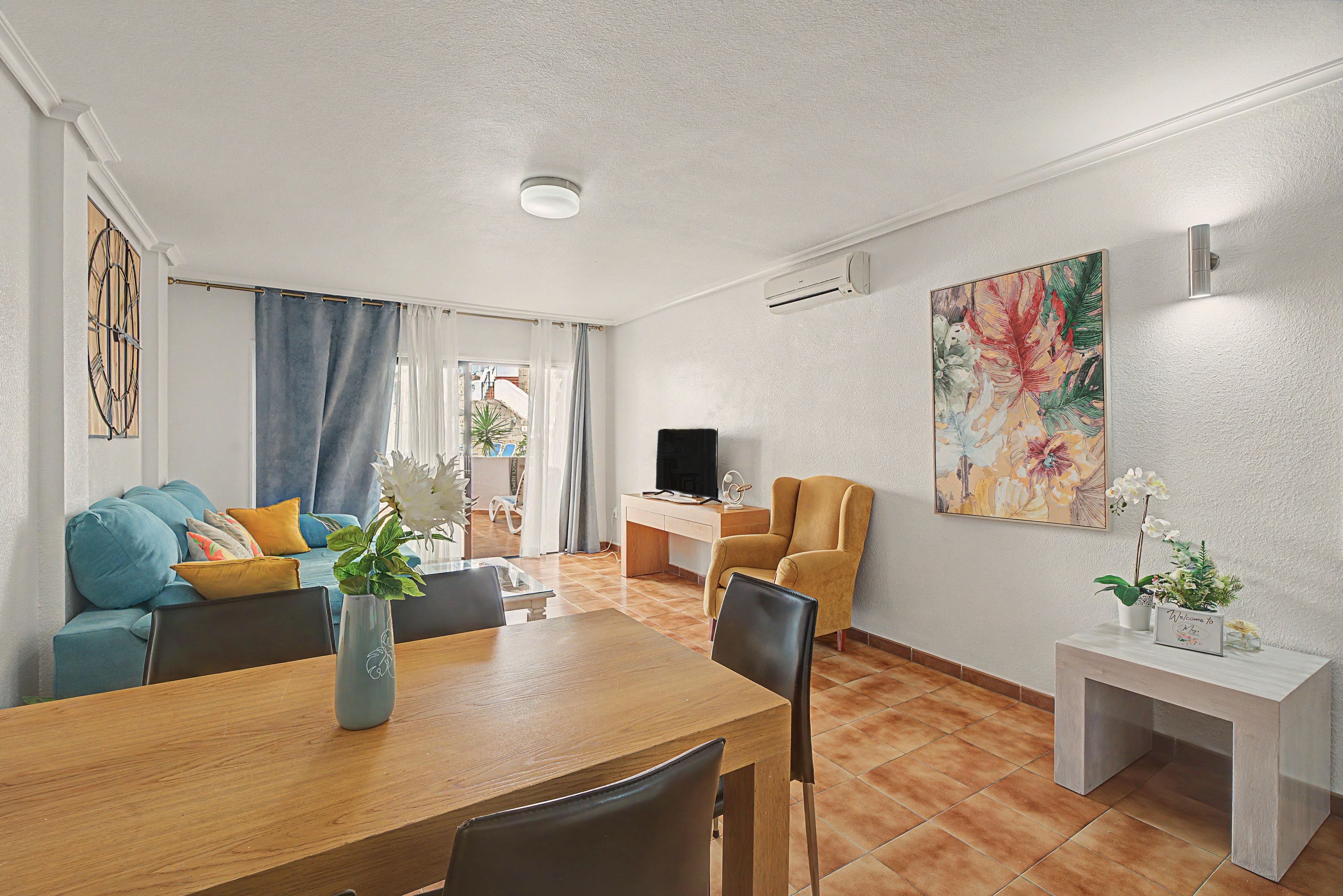 A modern living room with a sofa, a dining table, and a TV.