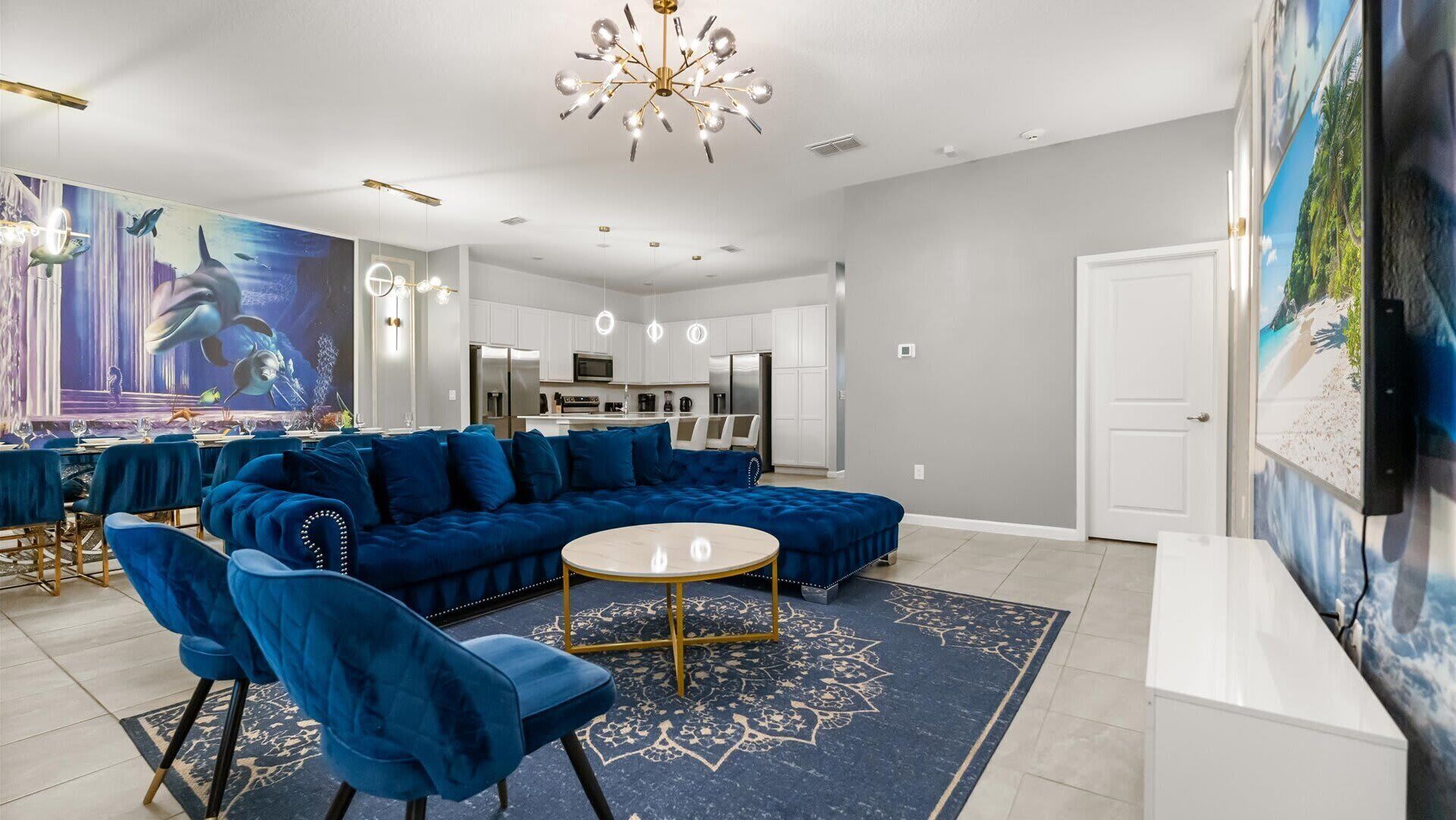 A modern living room with a blue sectional sofa, a round coffee table, and a large mural of a marine scene.