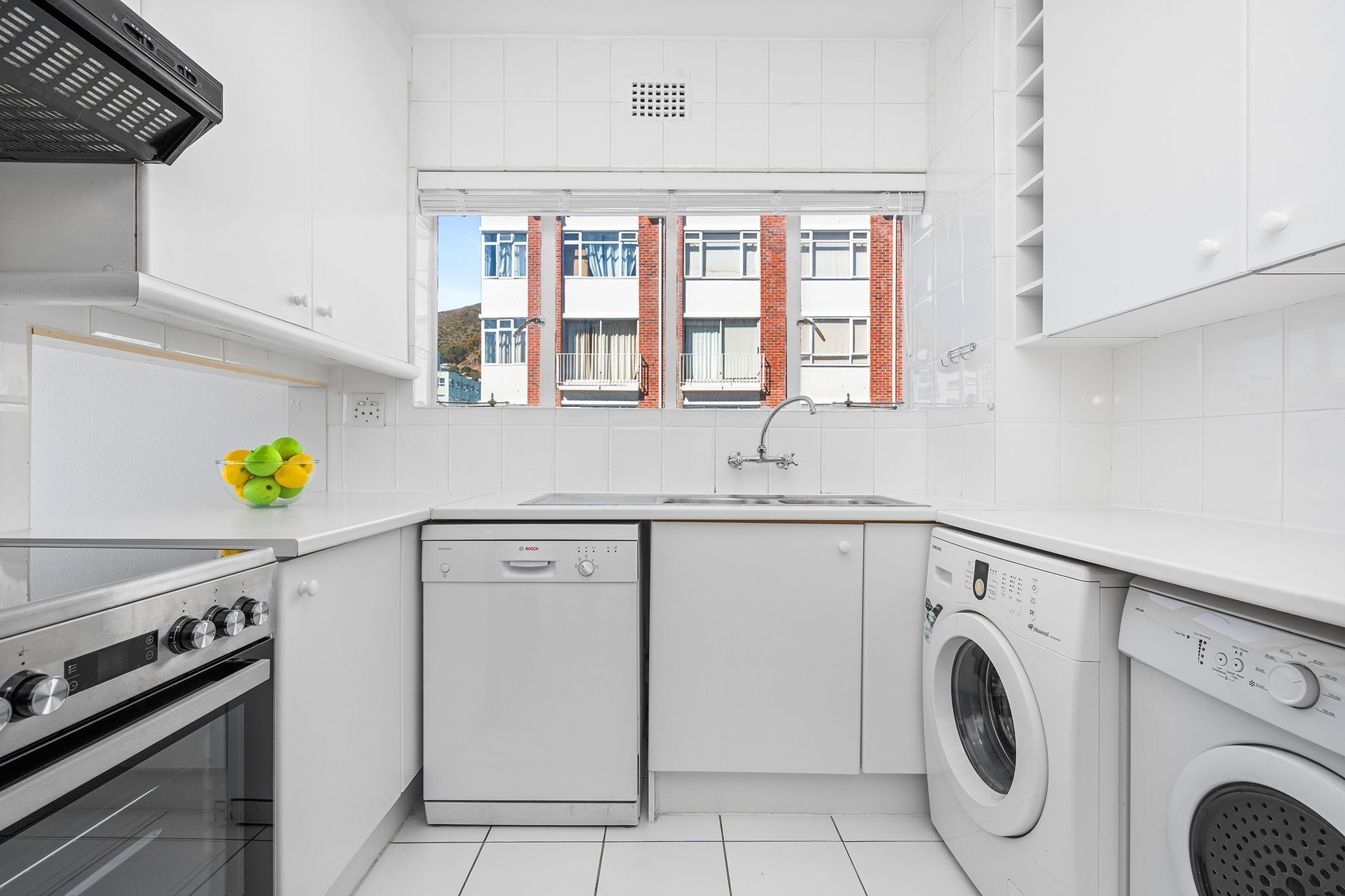 A compact kitchen with a dishwasher, washing machine, and oven.