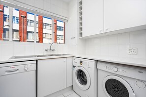 Una cocina moderna con electrodomésticos Bosch, un lavaplatos integrado y una ventana con vista a un edificio de ladrillo.