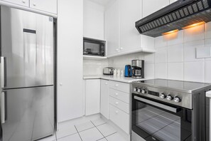 Una cocina moderna con refrigerador, microondas, estufa y horno de acero inoxidable.