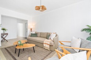 Una sala de estar moderna con un sofá, una mesa de centro de madera, una lámpara y un aplique colgante.