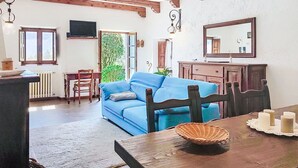 Una habitación con un sofá azul, una mesa de comedor de madera y un espejo grande.