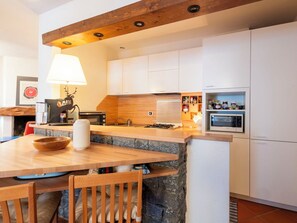 Eine moderne Küche mit weißen Schränken, einer Holz Arbeitsplatte, einer eingebauten Mikrowelle und einer Wand mit Steinverkleidung.