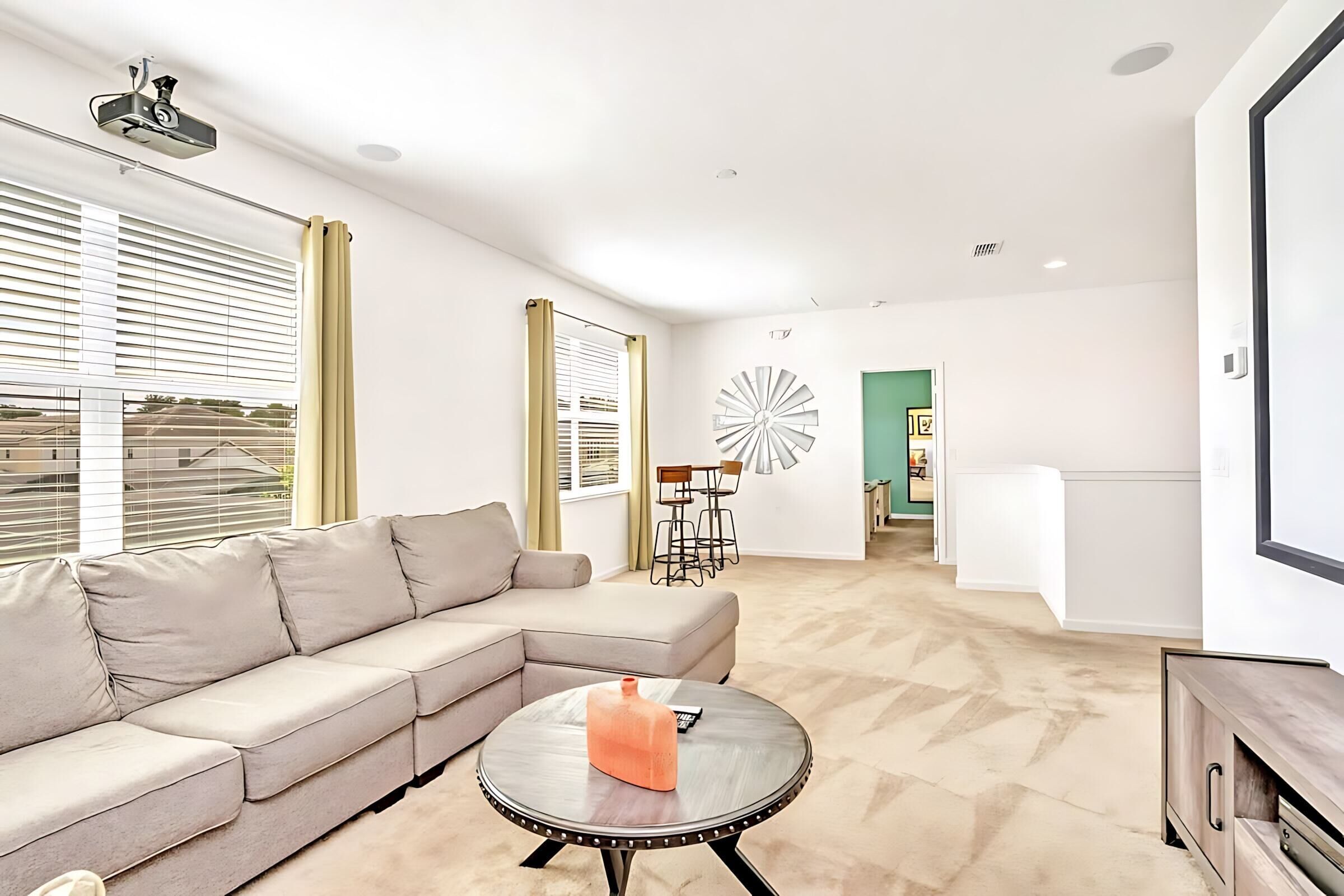 A modern living room with a beige sectional sofa, a round coffee table with a bottle, and a minimalist decor style.