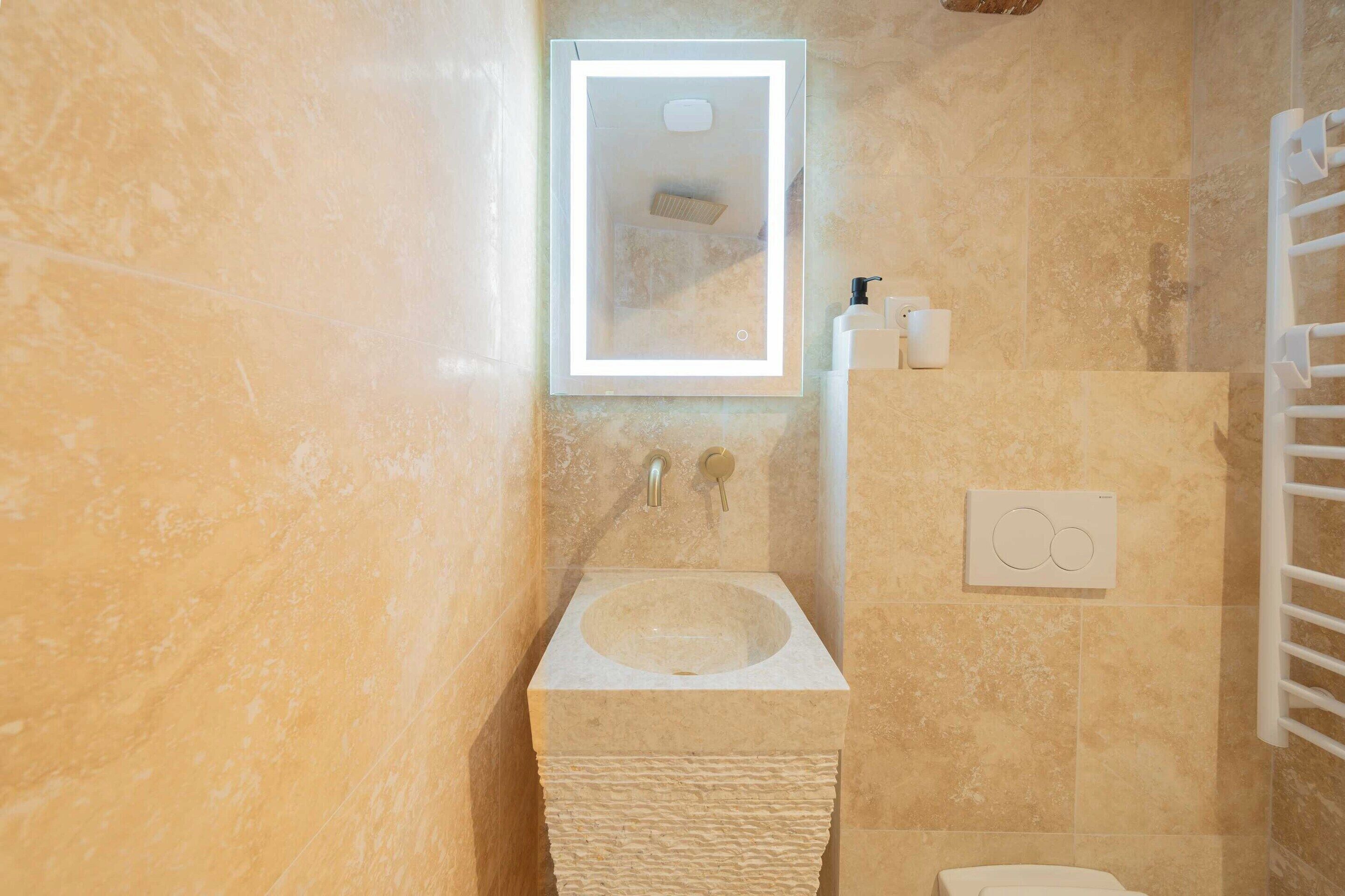 A bathroom with a marble sink, a mirror, a towel rack, and a wall-mounted heater.