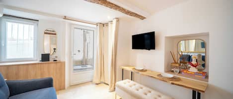 Una habitación moderna con sofá, banca, mesa de madera, televisor y espejo.