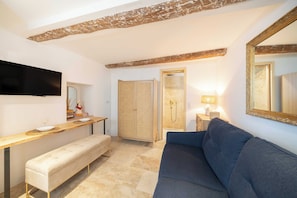 Una sala de estar moderna con sofá, banco, televisor de pantalla plana, mesa de madera y un espejo grande.