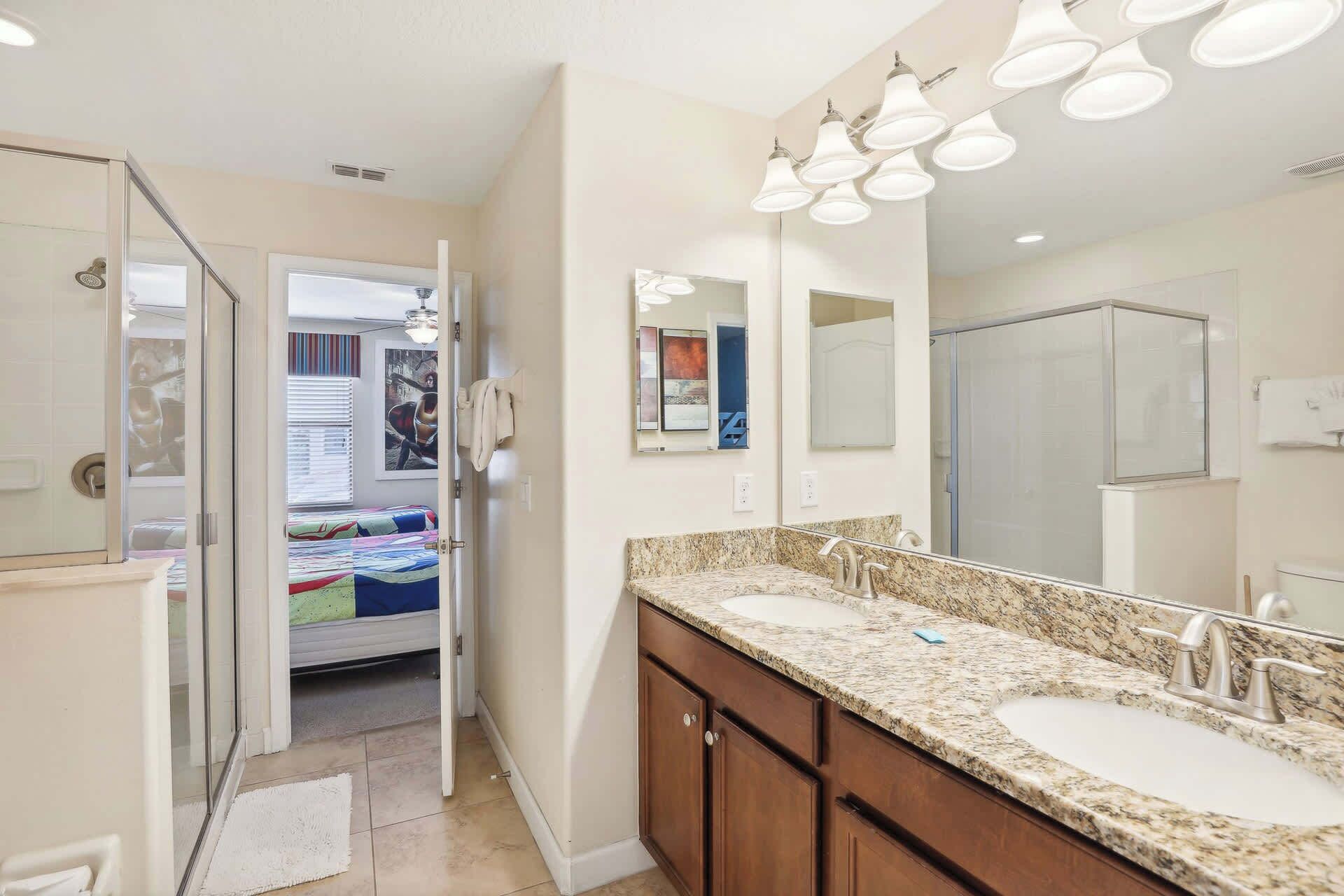 A bathroom with two sinks, a large mirror, and a shower.