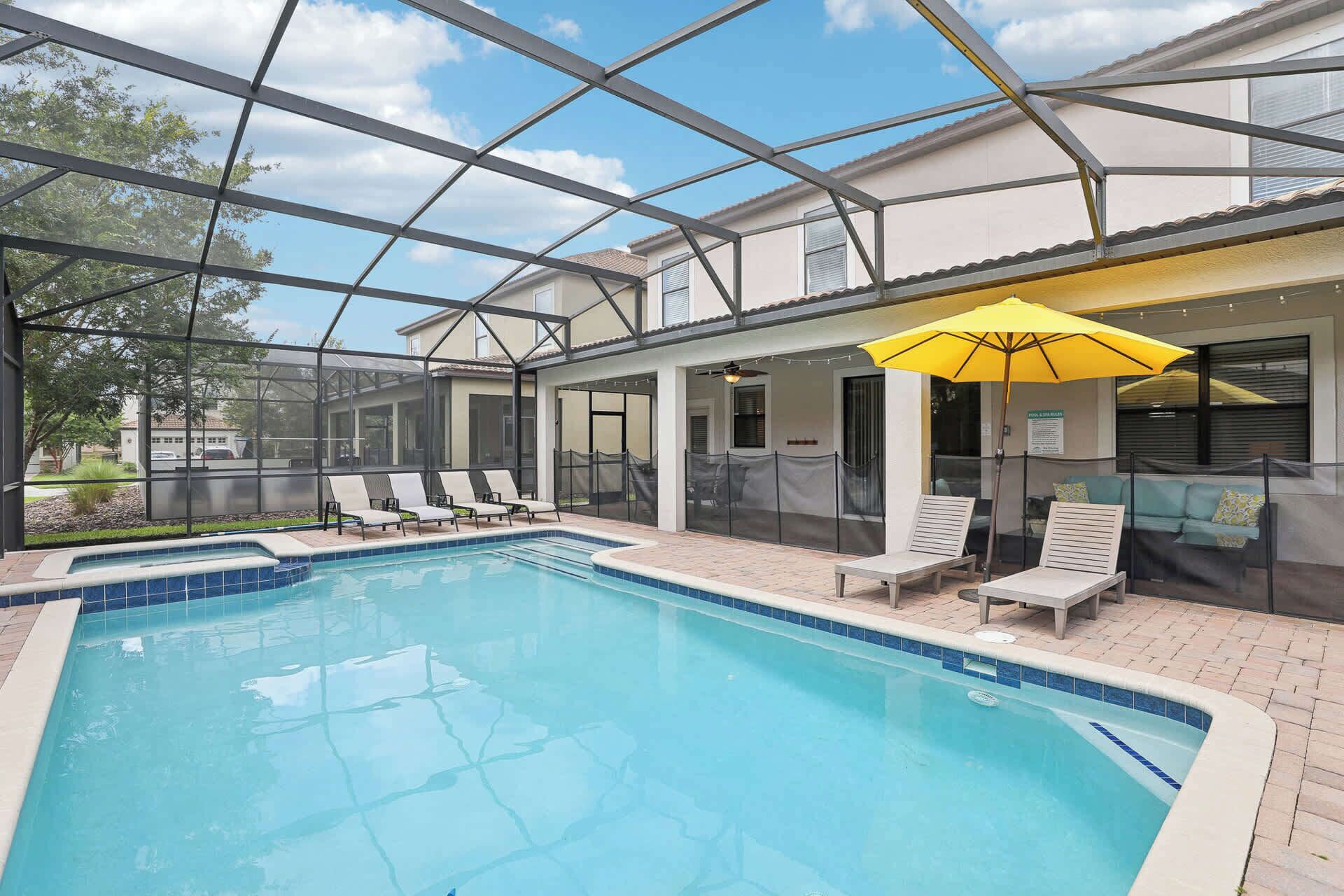 A pool area with a glass enclosure, lounge chairs, and a yellow umbrella.