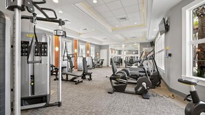 Een fitnessruimte met cardio-apparatuur, krachttoestellen en een spiegelwand.