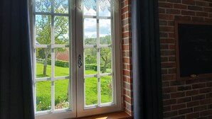 Ein Fenster mit Blick auf eine grüne Landschaft, eine Backsteinmauer und eine Tafel mit Schrift.