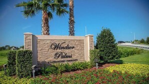A sign for Windsor Palms, a gated resort community, with a stone wall and palm trees in the background. - Windsor Palms Retreat: Pool, Resort Access & Minutes to Disney (Kissimmee)