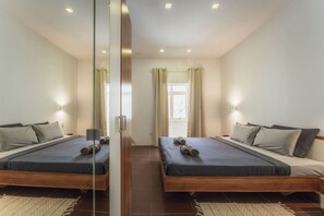 Ein Doppelzimmer mit zwei Betten, einer Glastrennwand und einem Vorhangfenster.