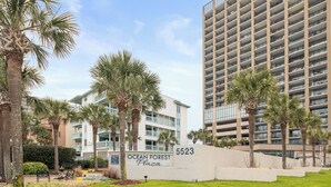 A multi-story building with balconies, a sign reading 'Ocean Forest Plaza,' and palm trees. - Perfect Peace:Spacious 1 BR King, Walk-in Shower, Big Balcony, Undeveloped Beach (Myrtle Beach)