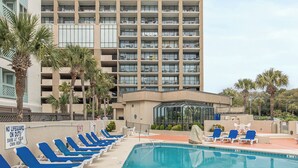 A tall hotel with a swimming pool and sun loungers. - Perfect Peace:Spacious 1 BR King, Walk-in Shower, Big Balcony, Undeveloped Beach (Myrtle Beach)