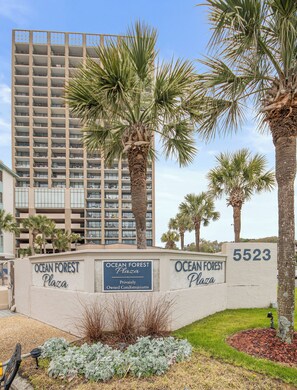 Um edifício com varandas e uma placa com o nome Ocean Forest Plaza.